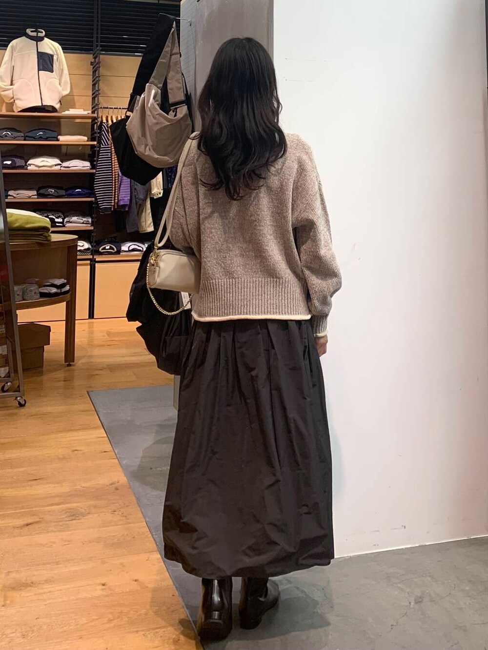 グレー系のスカート、ベージュ系のニット/セーター、ブラック系のブーツを着用したレディースの冬コーディネートの6枚目の写真
