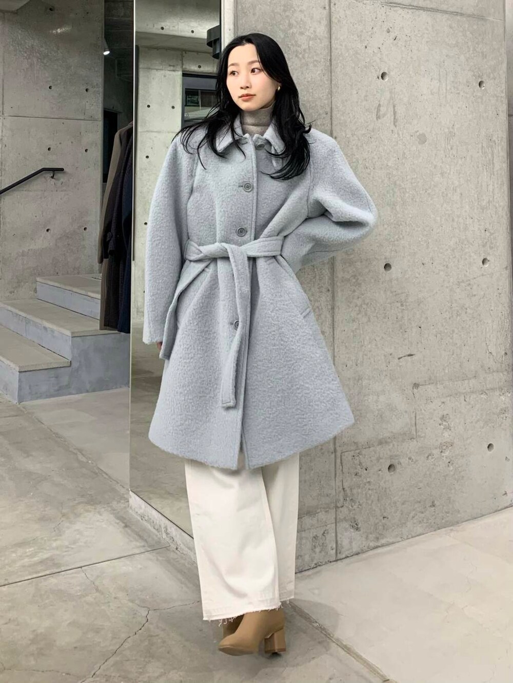 ホワイト系のデニムパンツ、ベージュ系のブーツ、ブルー系のステンカラーコートを着用したレディースの冬コーディネートの4枚目の写真