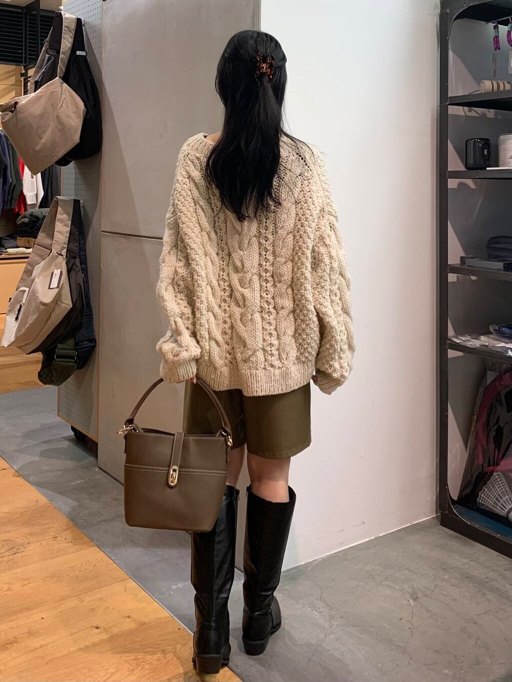 ホワイト系のニット/セーター、ベージュ系のハンドバッグ、ブラック系のブーツを着用したレディースの冬コーディネートの5枚目の写真