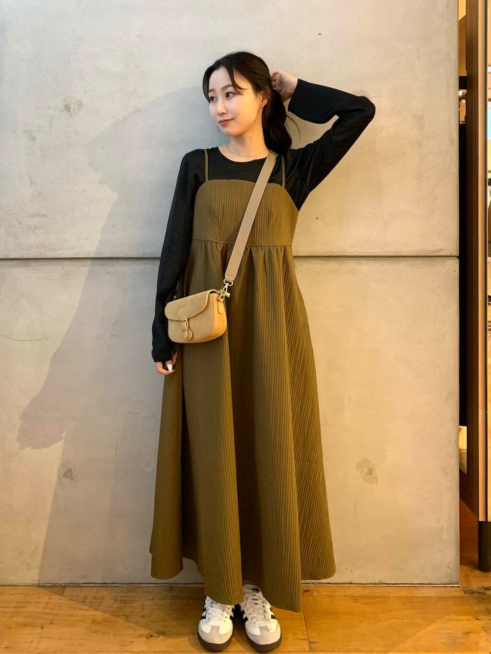 ベージュ系のショルダーバッグ、ホワイト系のスニーカー、ブラウン系のワンピースを着用したレディースの夏コーディネートの2枚目の写真