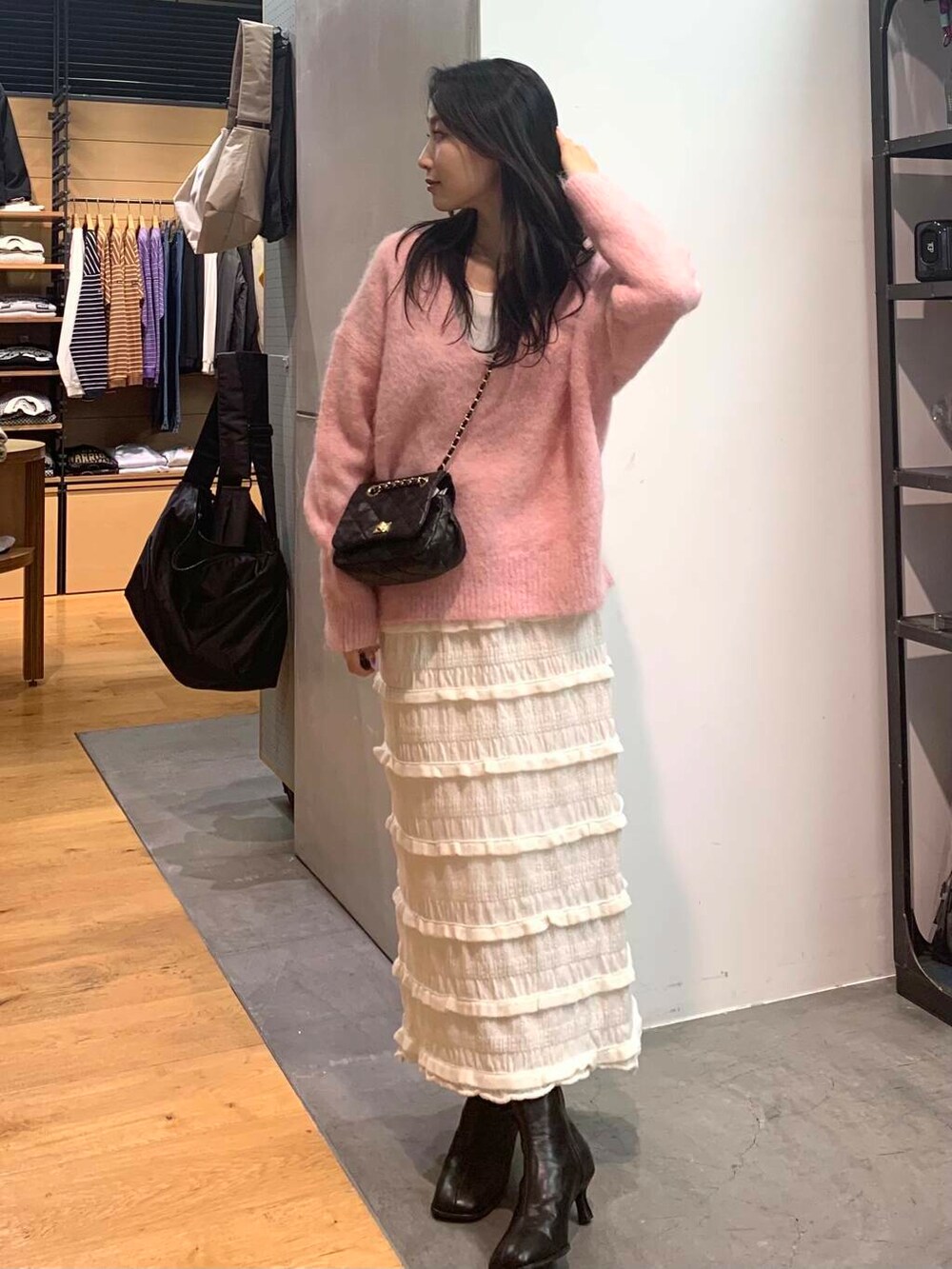 ブラック系のショルダーバッグ、ブラック系のブーツ、ピンク系のニット/セーターを着用したレディースの冬コーディネートの2枚目の写真