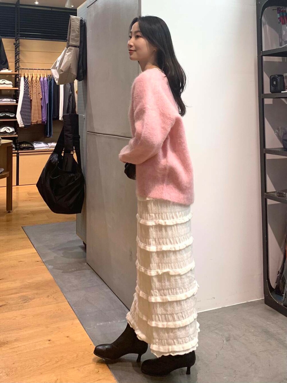 ブラック系のショルダーバッグ、ブラック系のブーツ、ピンク系のニット/セーターを着用したレディースの冬コーディネートの5枚目の写真