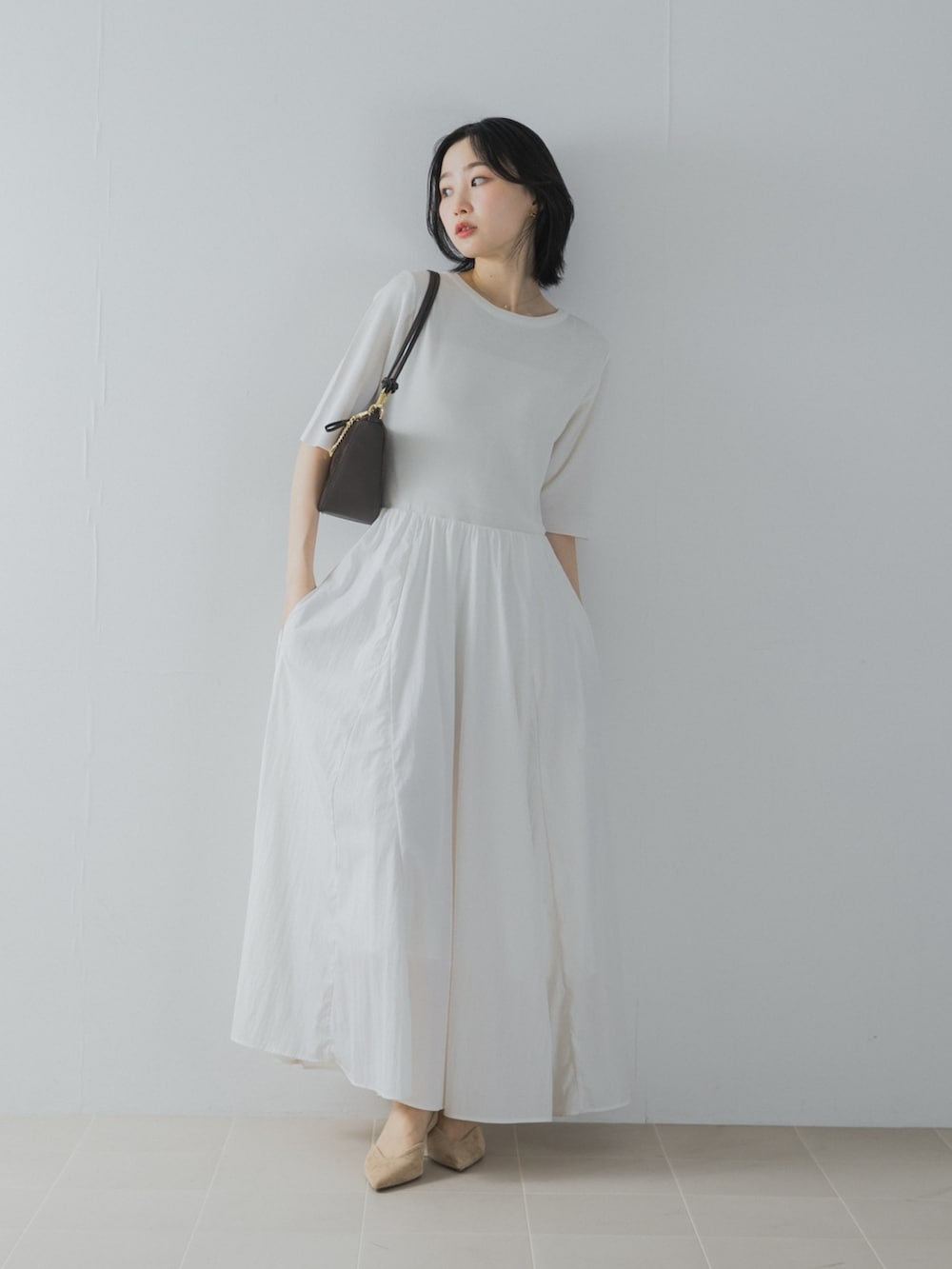 ホワイト系のワンピース、ブラウン系のショルダーバッグ、ベージュ系のパンプスを着用したレディースの夏コーディネートの2枚目の写真
