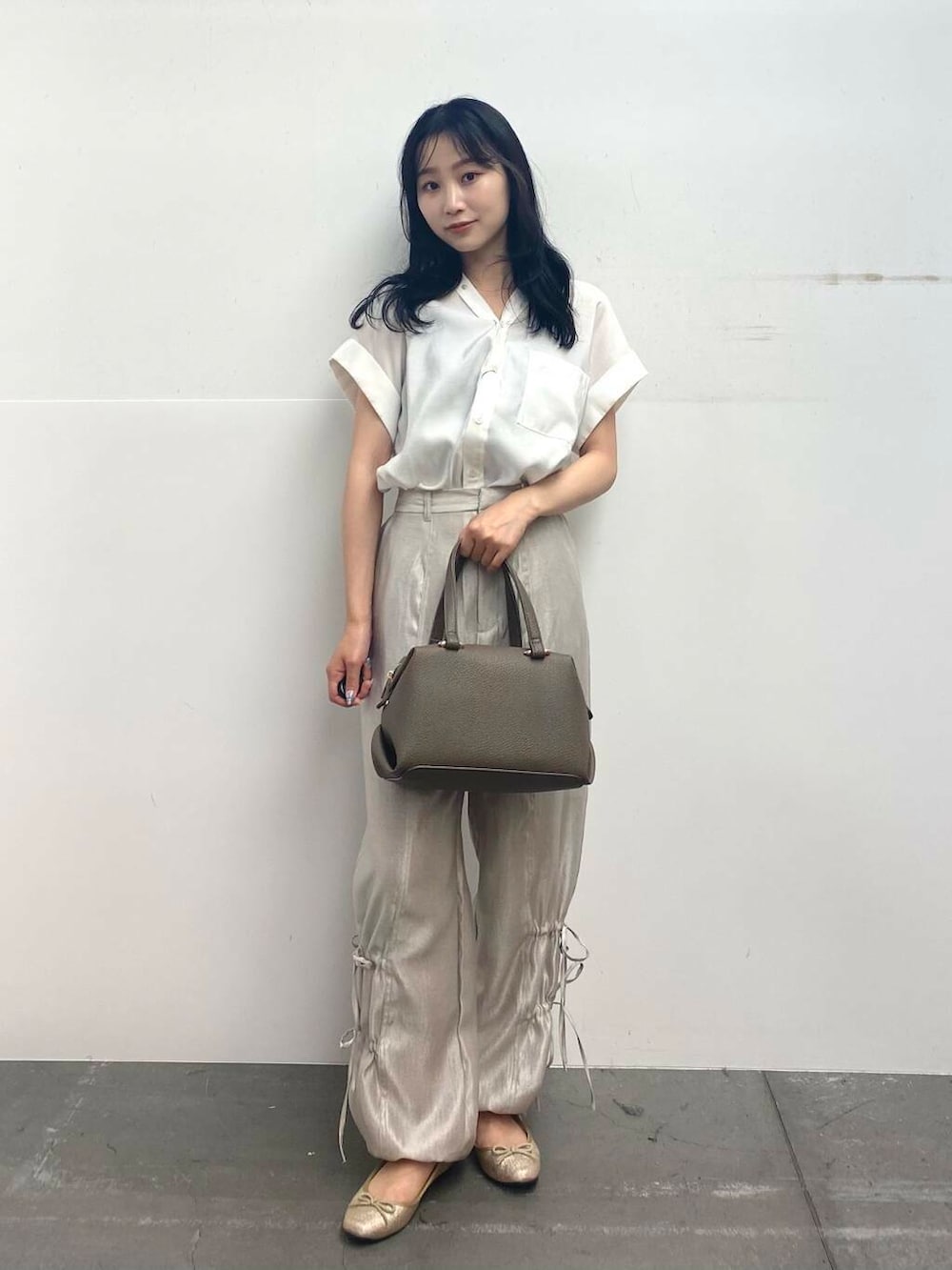 ベージュ系のハンドバッグ、ホワイト系のTシャツ/カットソー、ベージュ系のその他パンツを着用したレディースの夏コーディネートの2枚目の写真