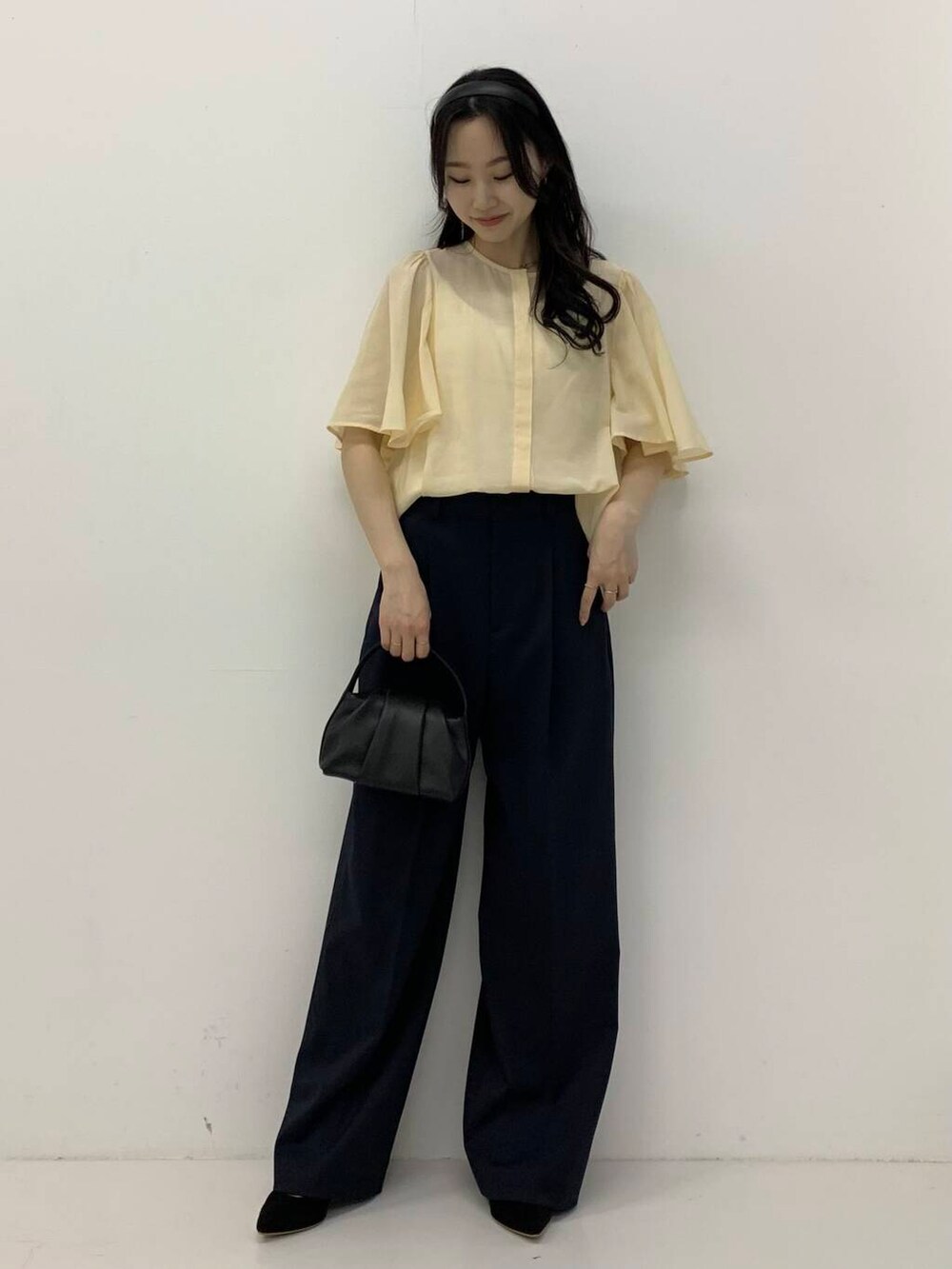 ブラック系のパンプス、ブラック系のハンドバッグ、ブルー系のその他パンツを着用したレディースの春コーディネートの2枚目の写真