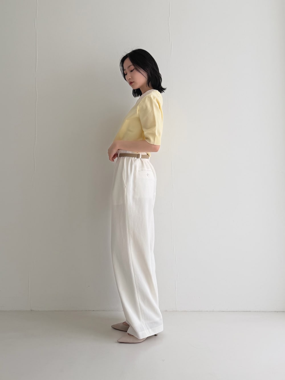 イエロー系のニット/セーター、ベージュ系のパンプス、ベージュ系のベルトを着用したレディースの春コーディネートの3枚目の写真