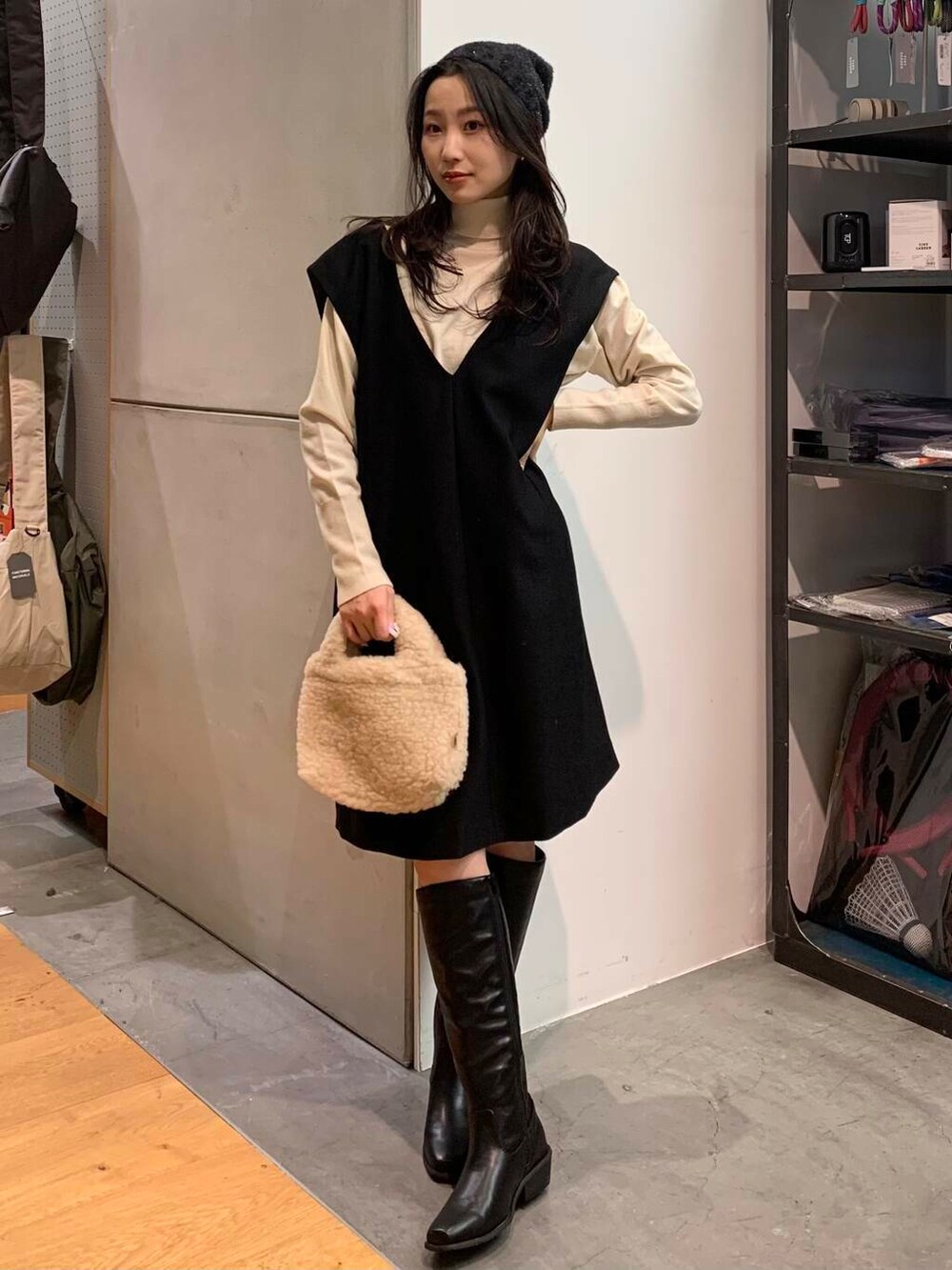 ブラック系のブーツ、ベージュ系のハンドバッグ、ブラック系のワンピースを着用したレディースの冬コーディネートの5枚目の写真