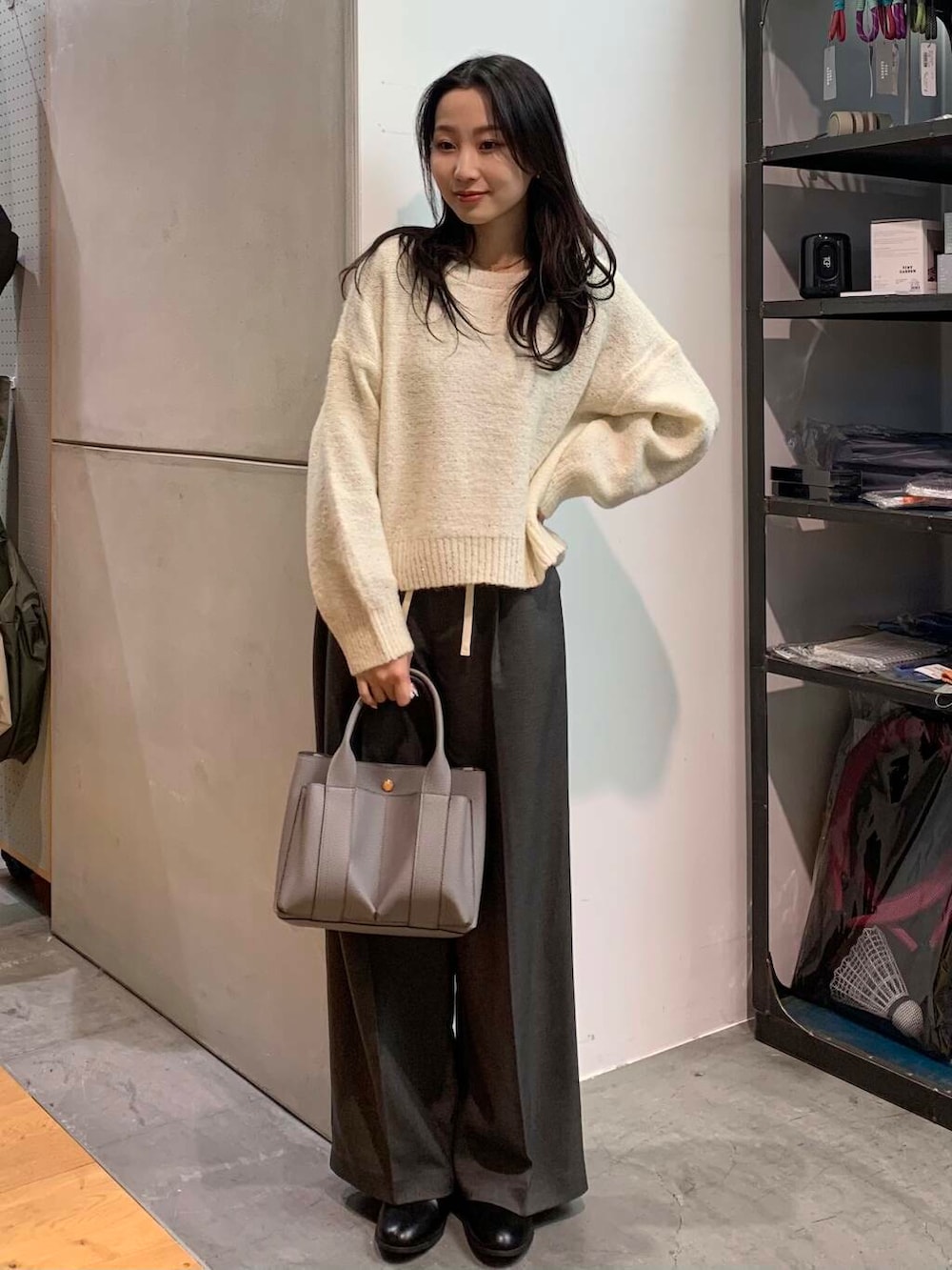 ブラック系のブーツ、グレー系のトートバッグ、ホワイト系のニット/セーターを着用したレディースの冬コーディネートの2枚目の写真
