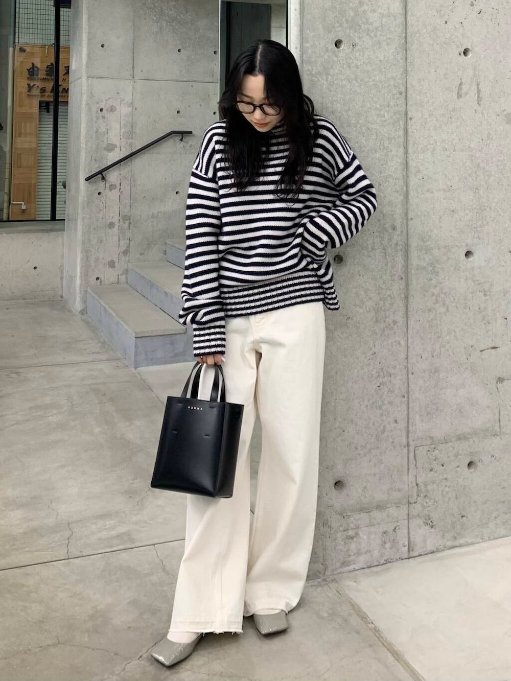 ホワイト系のデニムパンツ、ブラック系のハンドバッグ、グレー系のパンプスを着用したレディースの冬コーディネートの5枚目の写真