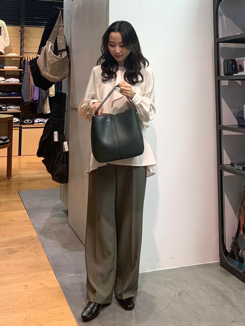 グリーン系のハンドバッグ、ブラック系のブーツ、ホワイト系のシャツ/ブラウスを着用したレディースの冬コーディネートの4枚目の写真