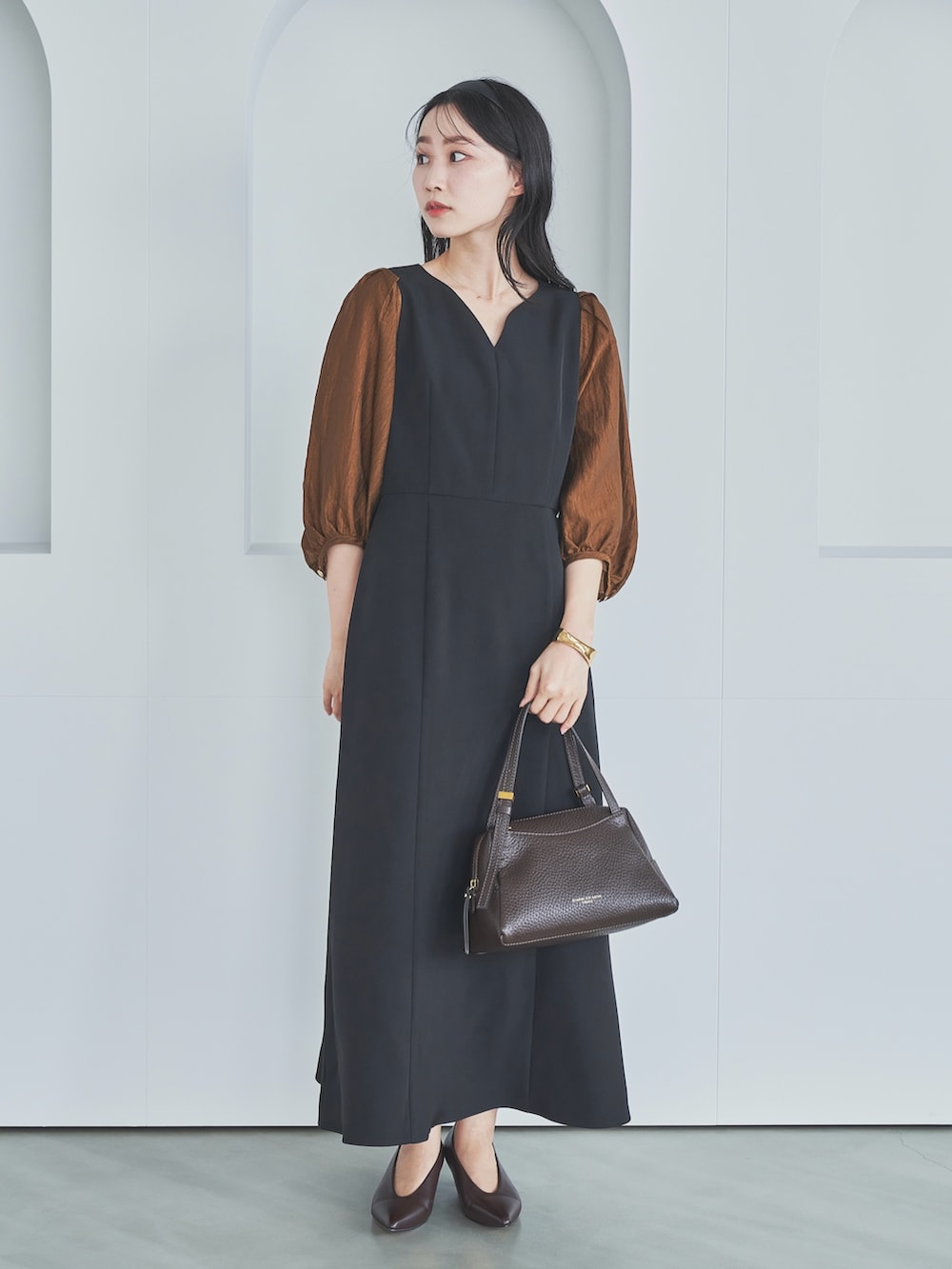 ブラック系のワンピース、ブラウン系のショルダーバッグ、ブラウン系のパンプスを着用したレディースの秋コーディネートの2枚目の写真