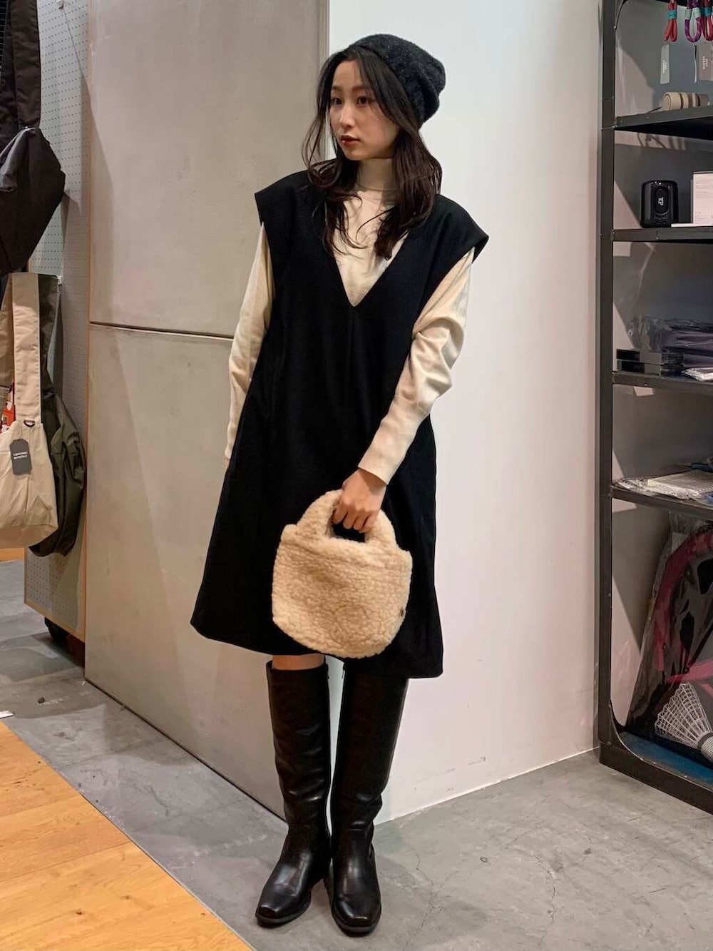 ブラック系のブーツ、ベージュ系のハンドバッグ、ブラック系のワンピースを着用したレディースの冬コーディネートの2枚目の写真