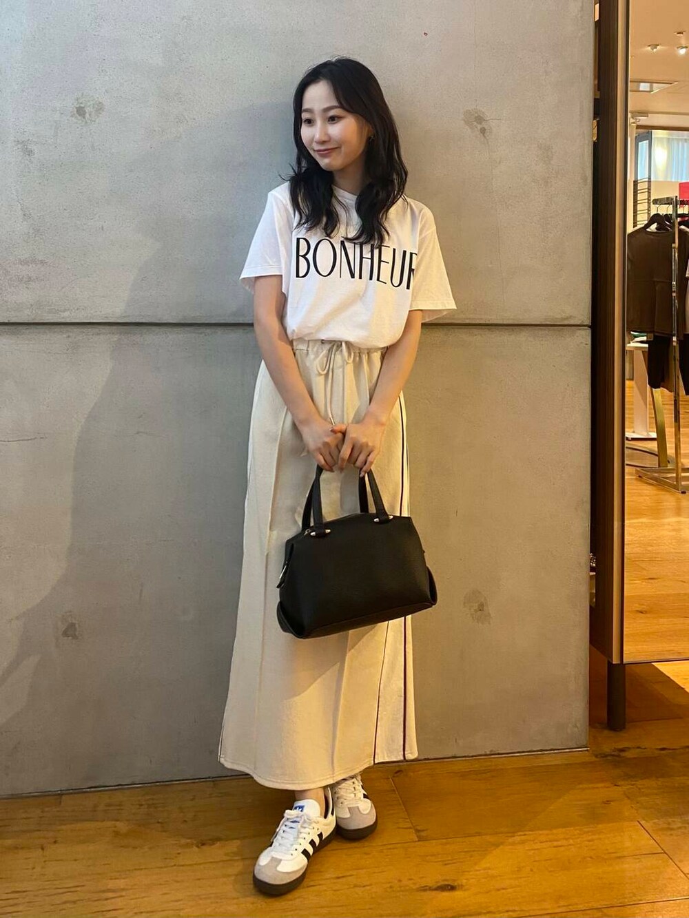 ブラック系のハンドバッグ、ホワイト系のTシャツ/カットソー、ホワイト系のスカートを着用したレディースの夏コーディネートの2枚目の写真