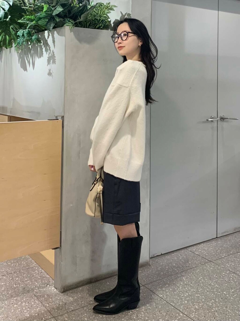 ホワイト系のボストンバッグ、ブラック系のブーツ、グレー系のその他パンツを着用したレディースの冬コーディネートの6枚目の写真