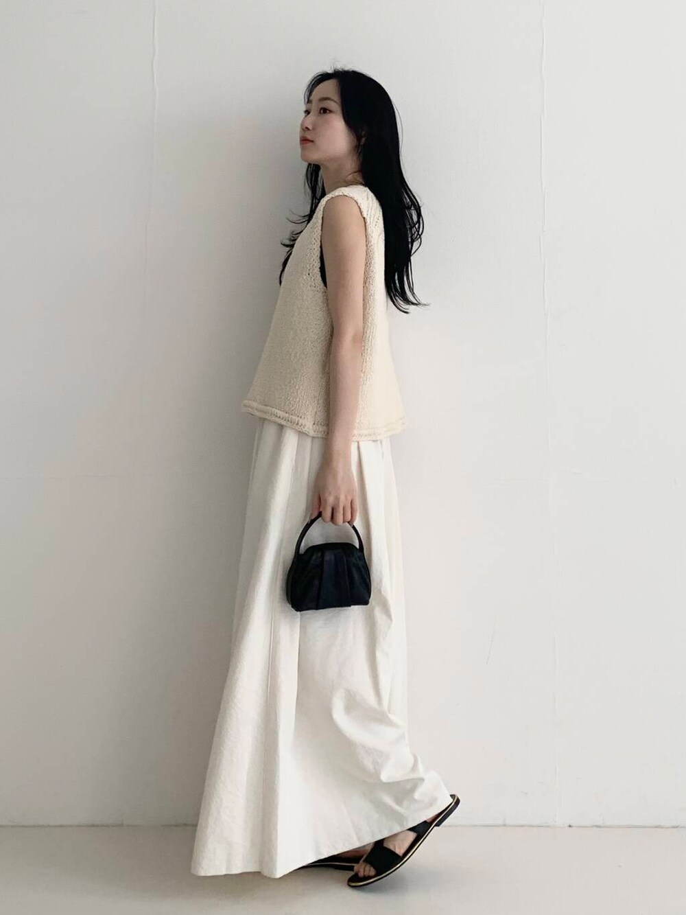 ブラック系のハンドバッグ、ホワイト系のベスト、ホワイト系のその他パンツを着用したレディースの春コーディネートの3枚目の写真