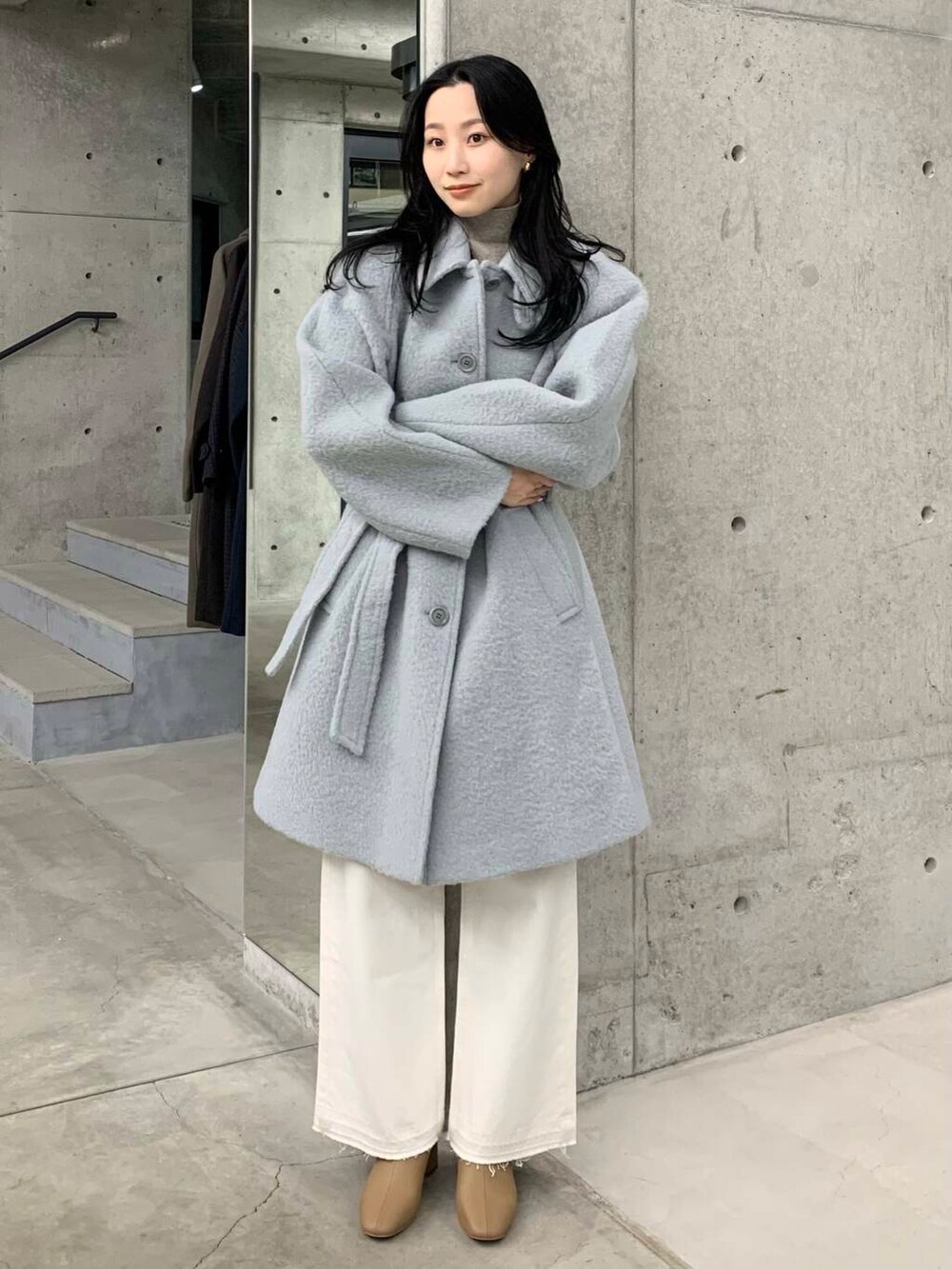 ホワイト系のデニムパンツ、ベージュ系のブーツ、ブルー系のステンカラーコートを着用したレディースの冬コーディネートの5枚目の写真