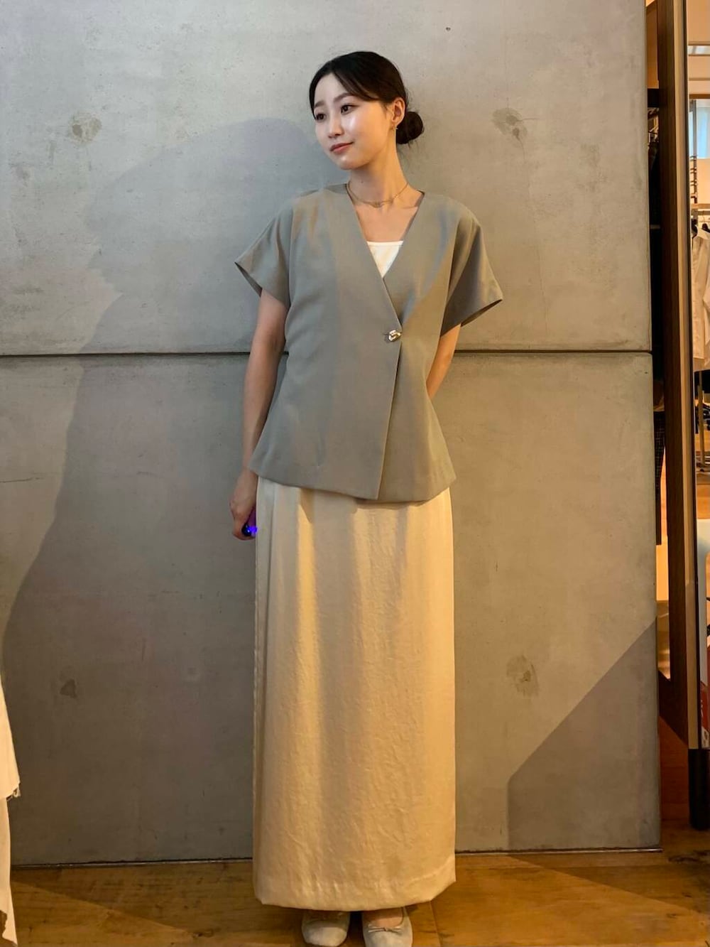 ホワイト系のスカート、ブラウン系のバレエシューズ、グレー系のベストを着用したレディースの秋コーディネートの3枚目の写真