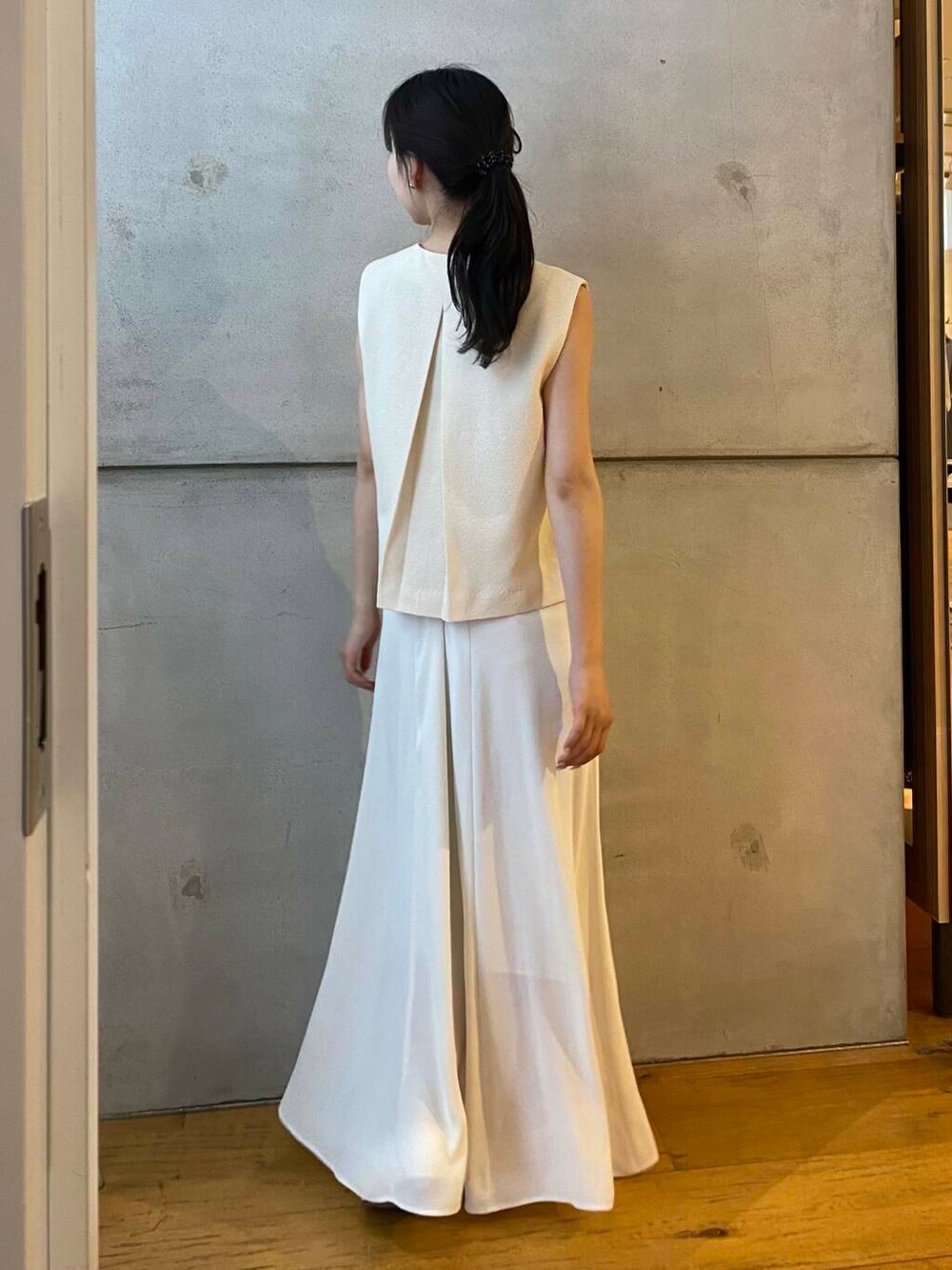 ホワイト系のパンプス、ホワイト系のベスト、ホワイト系のスカートを着用したレディースの夏コーディネートの5枚目の写真