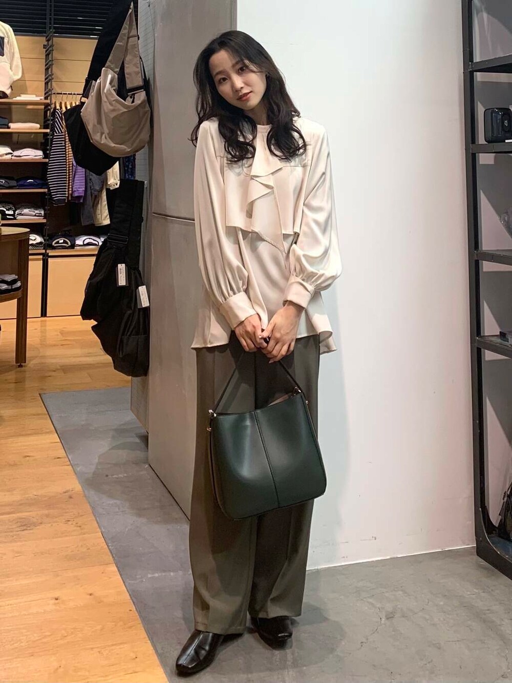 グリーン系のハンドバッグ、ブラック系のブーツ、ホワイト系のシャツ/ブラウスを着用したレディースの冬コーディネートの2枚目の写真