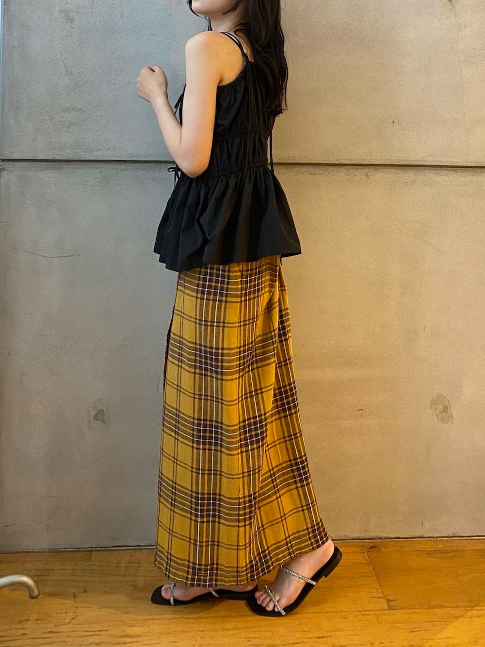 イエロー系のスカート、ブラック系のベスト、ブラック系のサンダルを着用したレディースの夏コーディネートの5枚目の写真