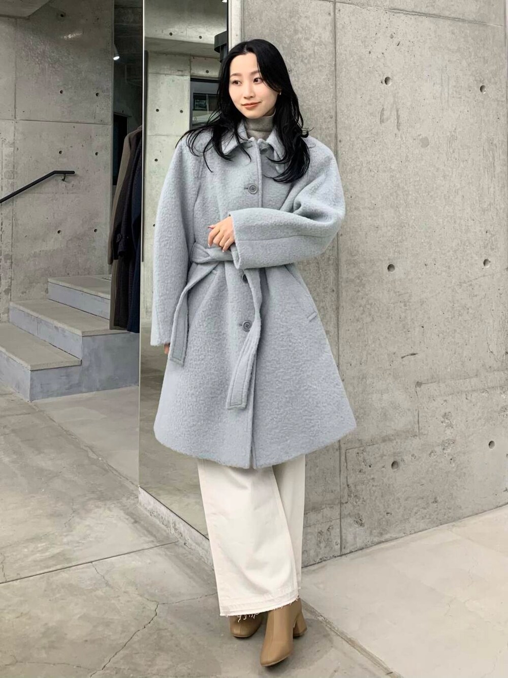 ホワイト系のデニムパンツ、ベージュ系のブーツ、ブルー系のステンカラーコートを着用したレディースの冬コーディネートの2枚目の写真