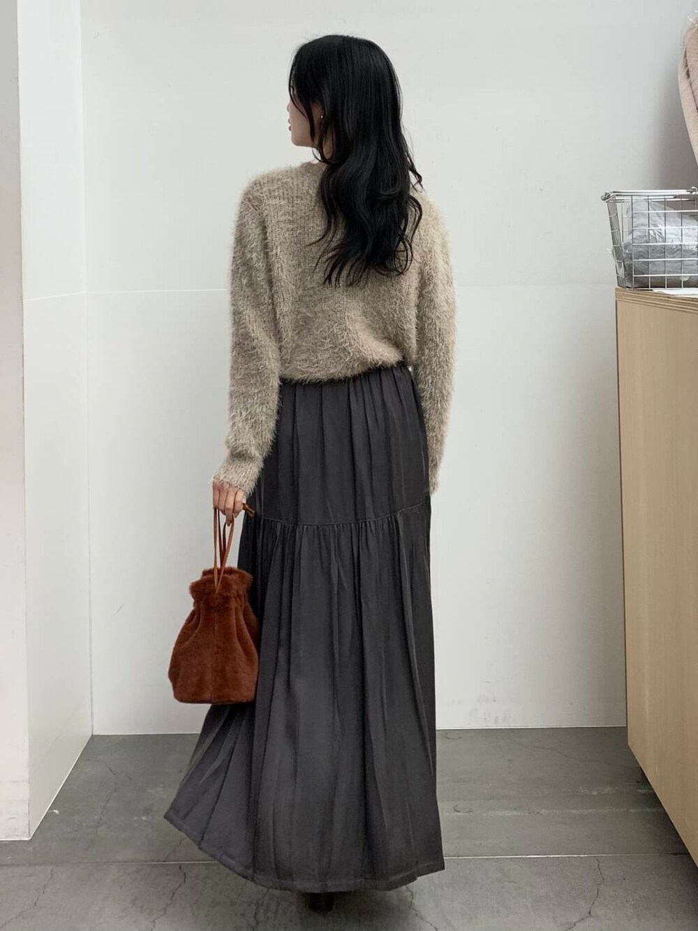 ブラック系のブーツ、ブラウン系のショルダーバッグ、グレー系のスカートを着用したレディースの冬コーディネートの6枚目の写真