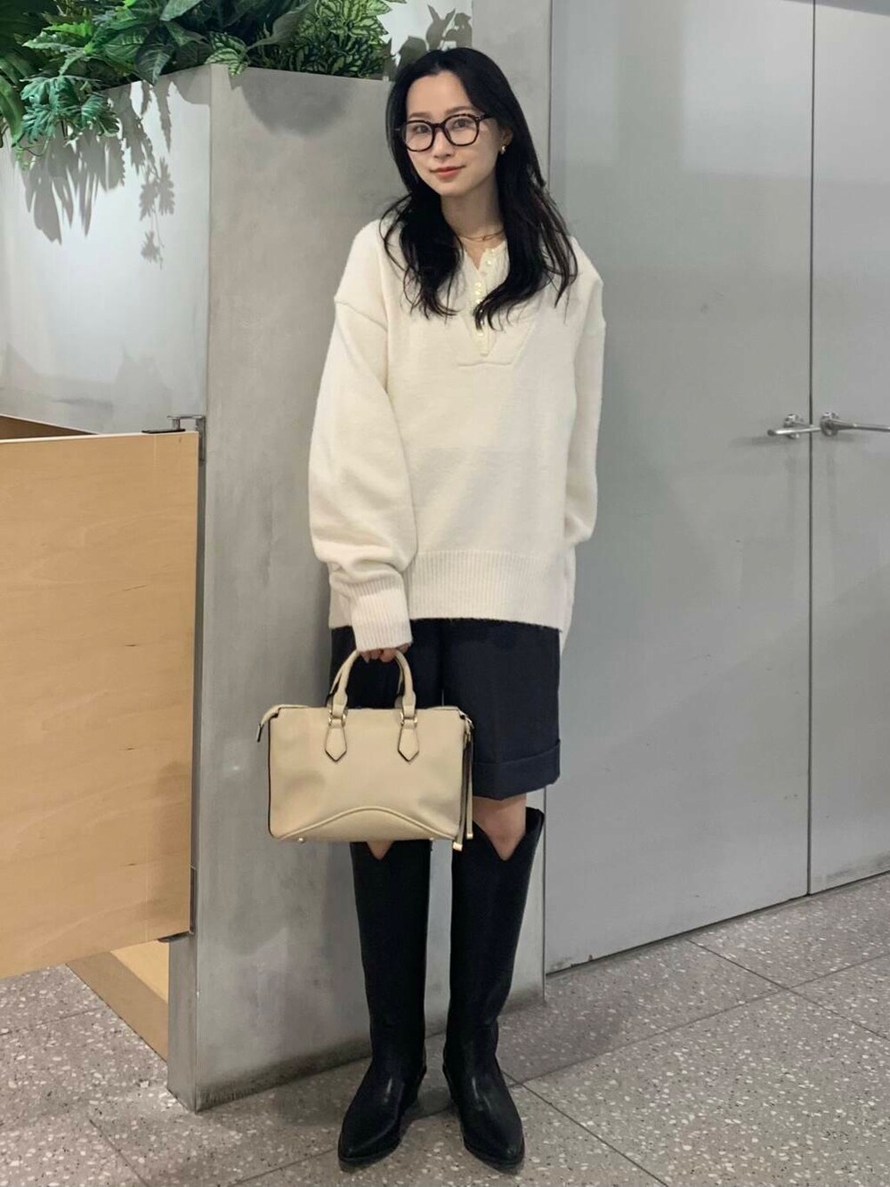 ホワイト系のボストンバッグ、ブラック系のブーツ、グレー系のその他パンツを着用したレディースの冬コーディネートの4枚目の写真