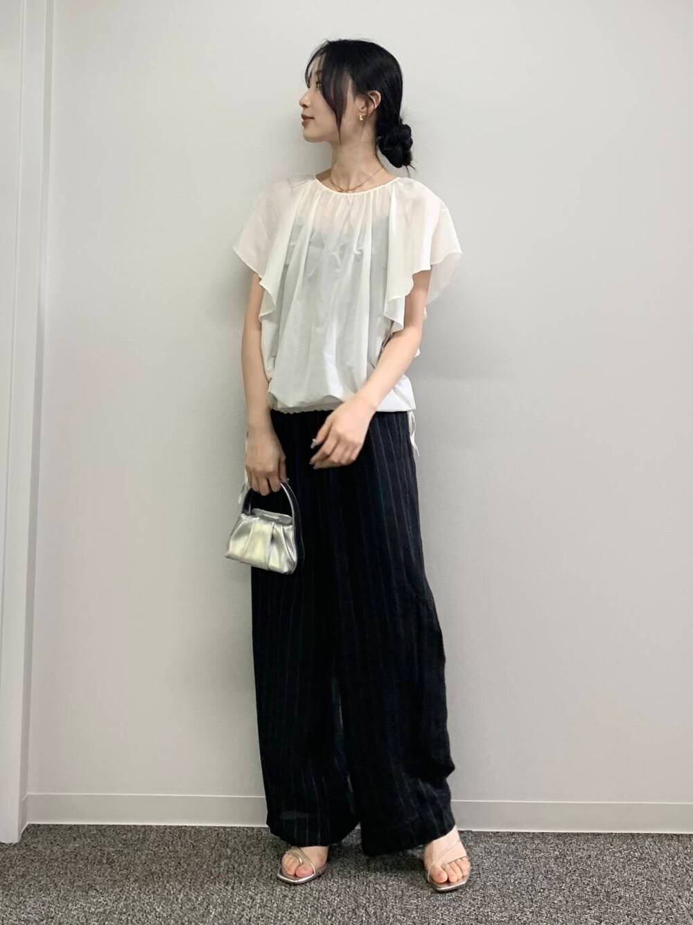 シルバー系のハンドバッグ、ブラック系のその他パンツ、ホワイト系のシャツ/ブラウスを着用したレディースの春コーディネートの4枚目の写真