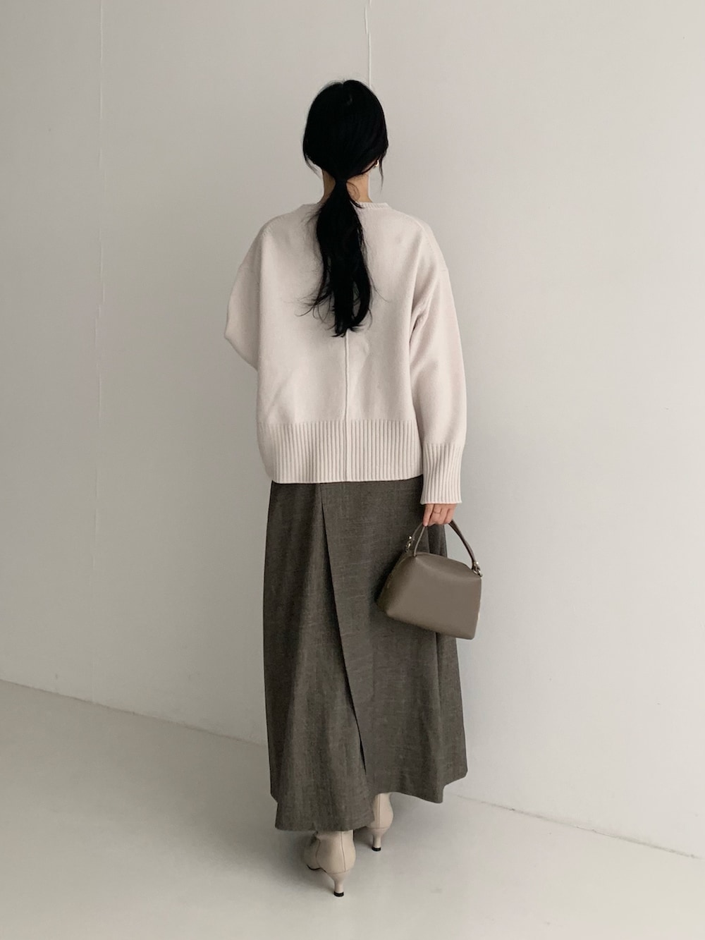 ホワイト系のニット/セーター、ブラウン系のスカート、ブラウン系のハンドバッグを着用したレディースの秋コーディネートの4枚目の写真