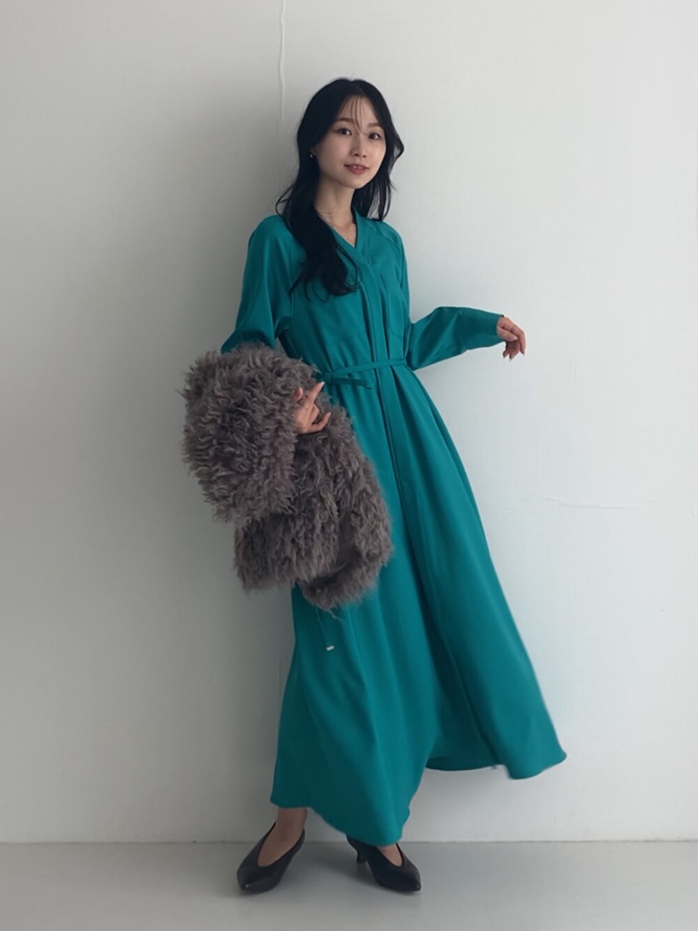 グリーン系のワンピース、グレー系のベスト、ブラウン系のパンプスを着用したレディースの秋コーディネートの2枚目の写真