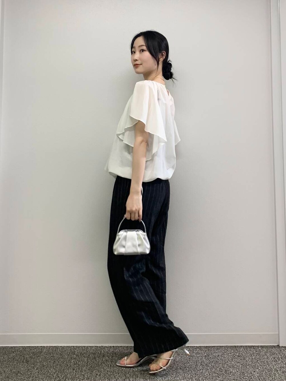 シルバー系のハンドバッグ、ブラック系のその他パンツ、ホワイト系のシャツ/ブラウスを着用したレディースの春コーディネートの5枚目の写真