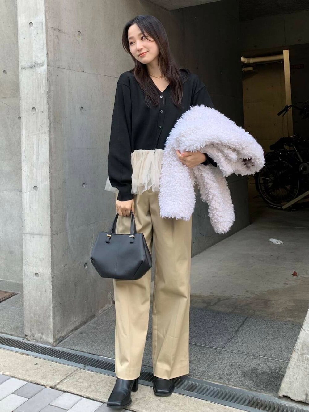 ブラック系のショルダーバッグ、ブラック系のブーツ、ベージュ系のチノパンツを着用したレディースの冬コーディネートの3枚目の写真