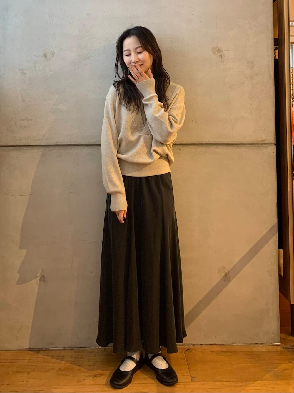 グレー系のスカート、ベージュ系のタンクトップ、ベージュ系のニット/セーターを着用したレディースの秋コーディネートの2枚目の写真