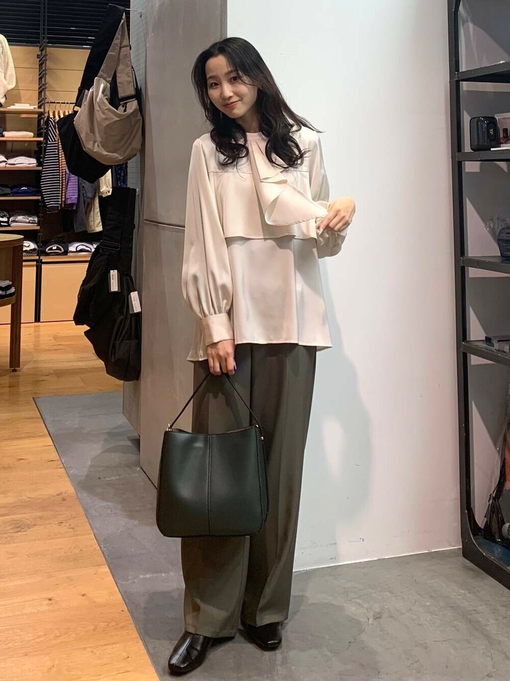 グリーン系のハンドバッグ、ブラック系のブーツ、ホワイト系のシャツ/ブラウスを着用したレディースの冬コーディネートの3枚目の写真