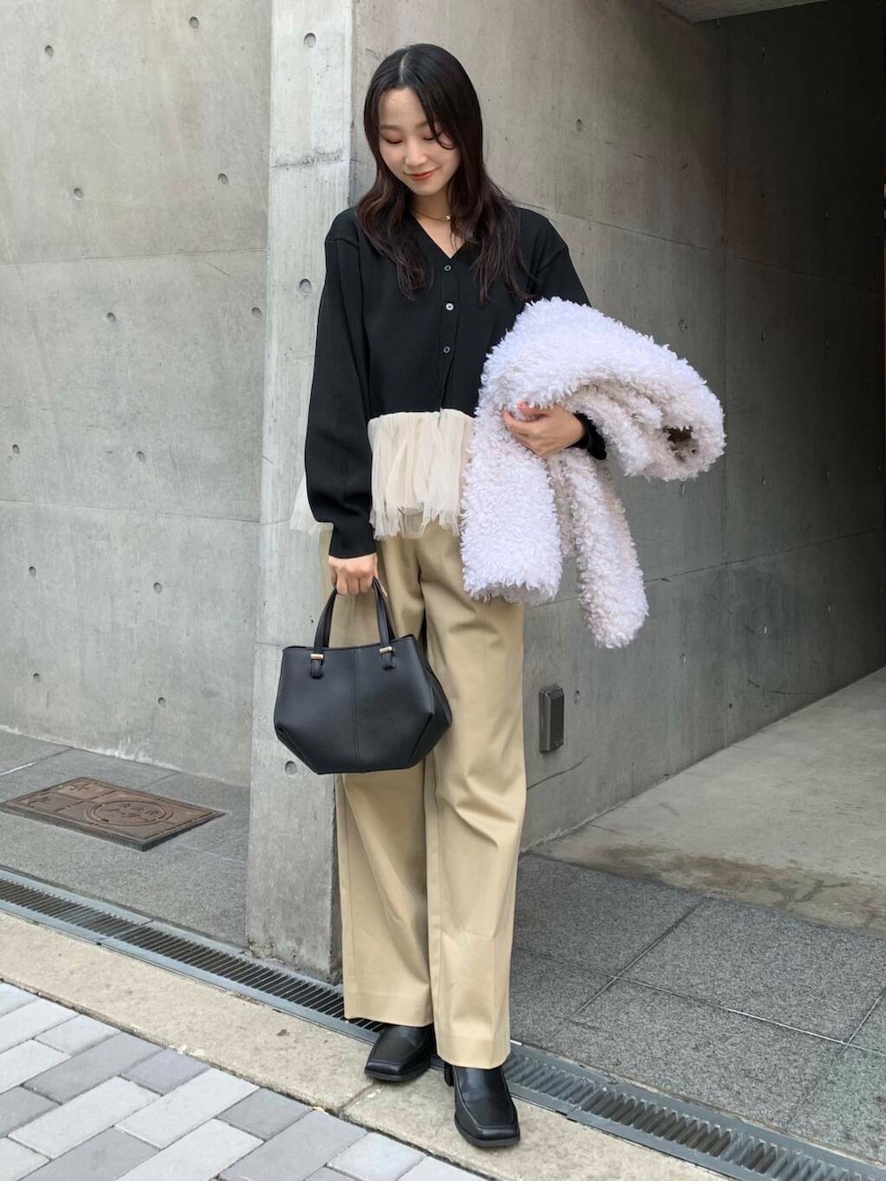 ブラック系のショルダーバッグ、ブラック系のブーツ、ベージュ系のチノパンツを着用したレディースの冬コーディネートの2枚目の写真