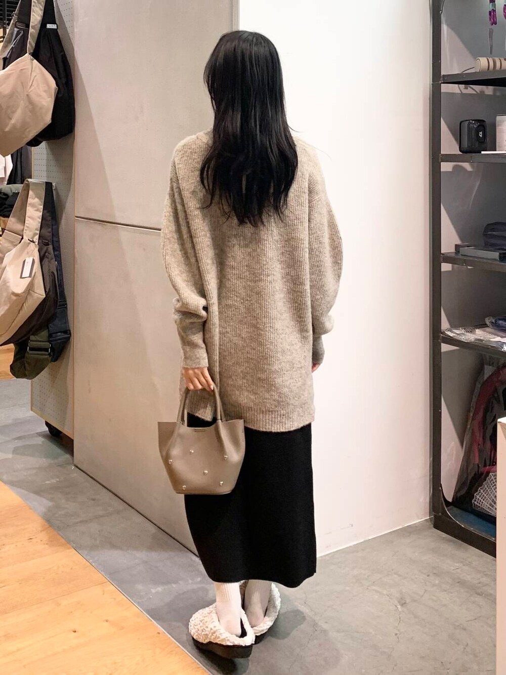 グレー系のショルダーバッグ、ベージュ系のニット/セーター、ブラック系のスカートを着用したレディースの冬コーディネートの4枚目の写真