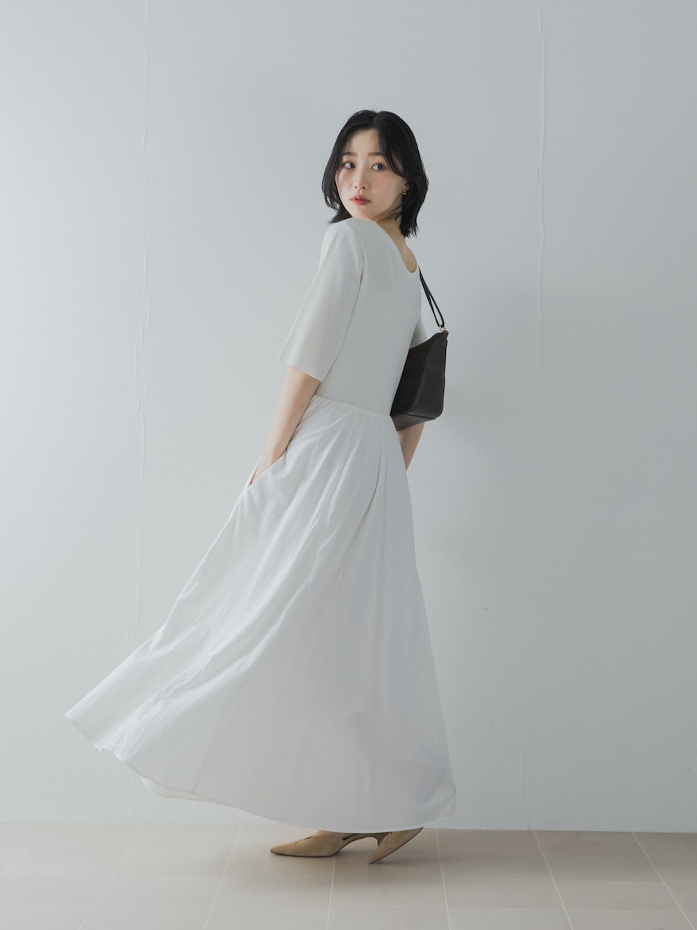 ホワイト系のワンピース、ブラウン系のショルダーバッグ、ベージュ系のパンプスを着用したレディースの夏コーディネートの4枚目の写真