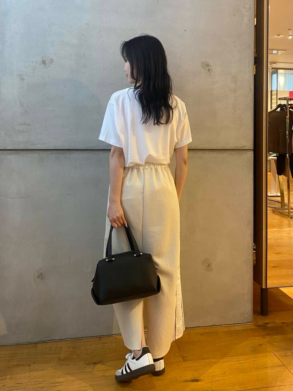 ブラック系のハンドバッグ、ホワイト系のTシャツ/カットソー、ホワイト系のスカートを着用したレディースの夏コーディネートの6枚目の写真