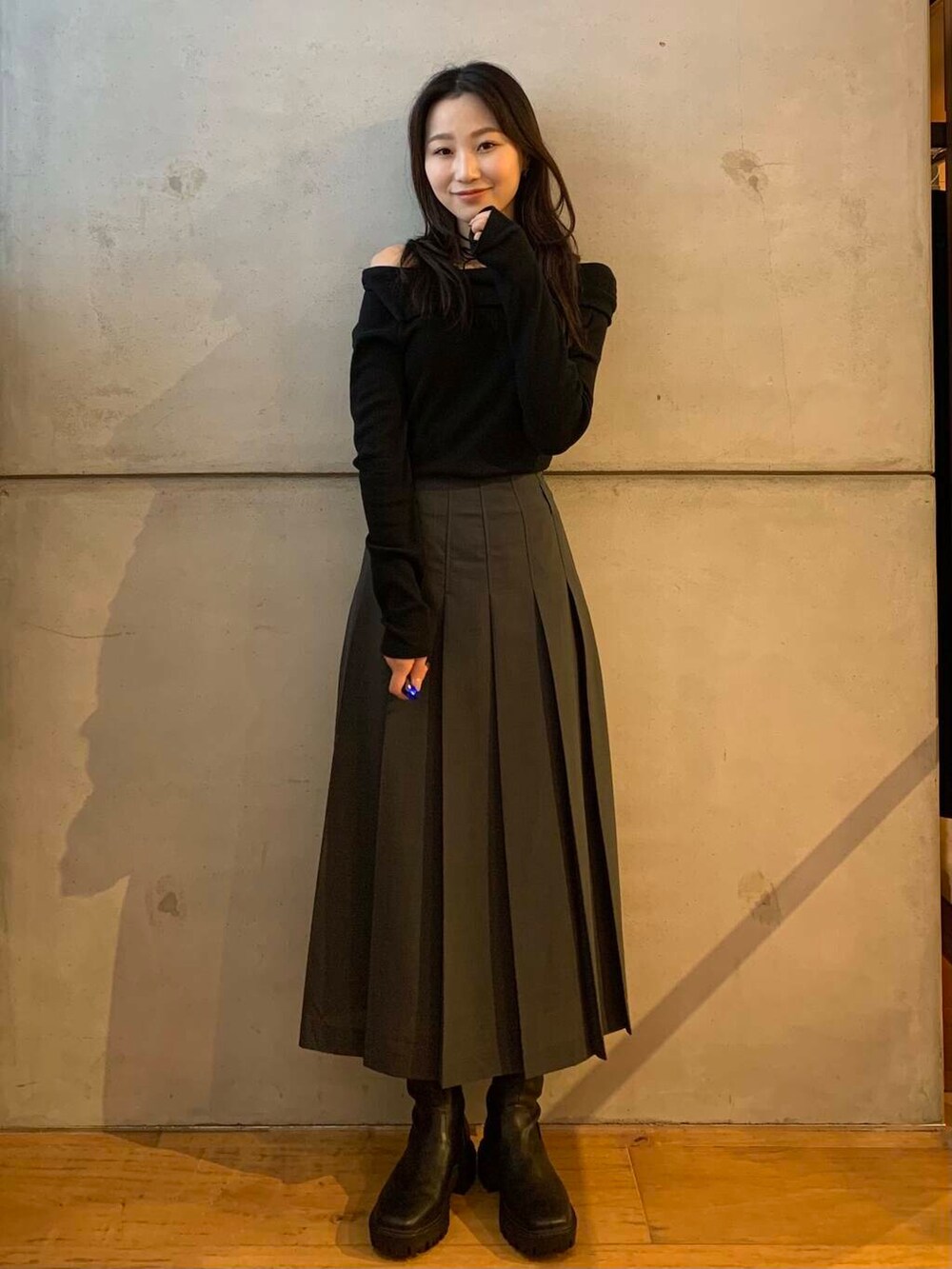 グレー系のスカート、ブラック系のブーツ、ブラック系のTシャツ/カットソーを着用したレディースの秋コーディネートの5枚目の写真