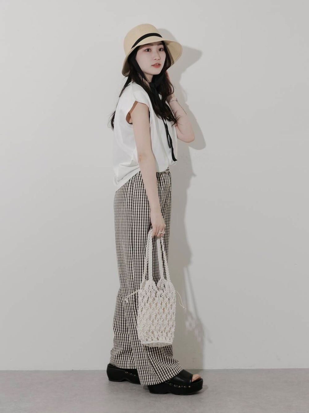 ホワイト系のTシャツ/カットソー、ホワイト系のハンドバッグ、ブラック系のサンダルを着用したレディースの春コーディネートの3枚目の写真