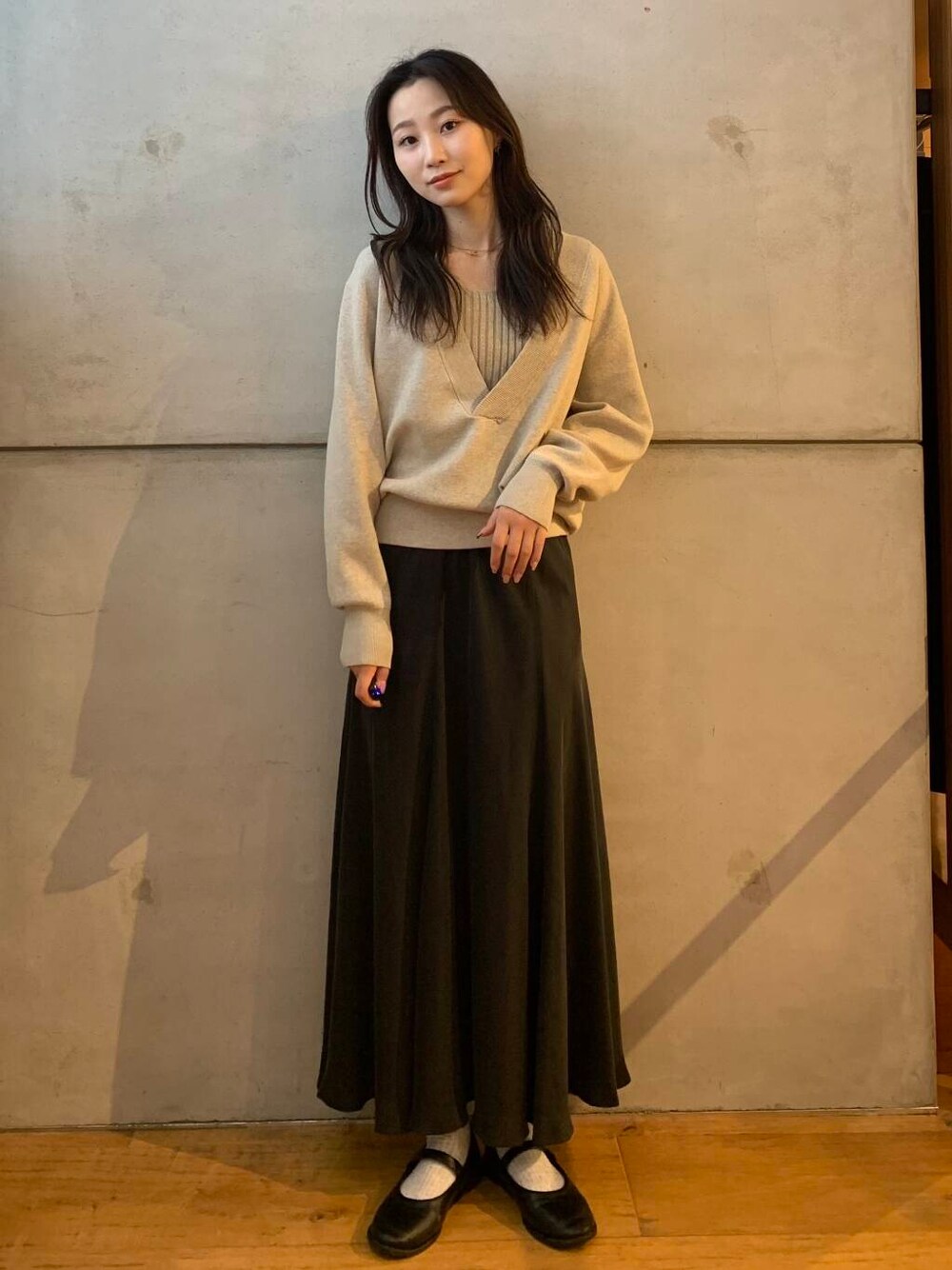 グレー系のスカート、ベージュ系のタンクトップ、ベージュ系のニット/セーターを着用したレディースの秋コーディネートの3枚目の写真