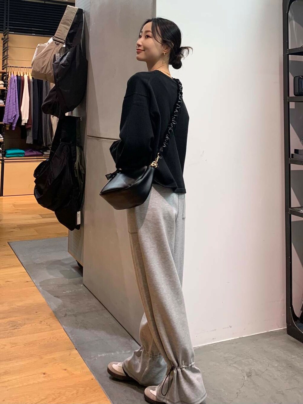 ホワイト系のスニーカー、ブラック系のカーディガン/ボレロ、ブラック系のショルダーバッグを着用したレディースの冬コーディネートの3枚目の写真