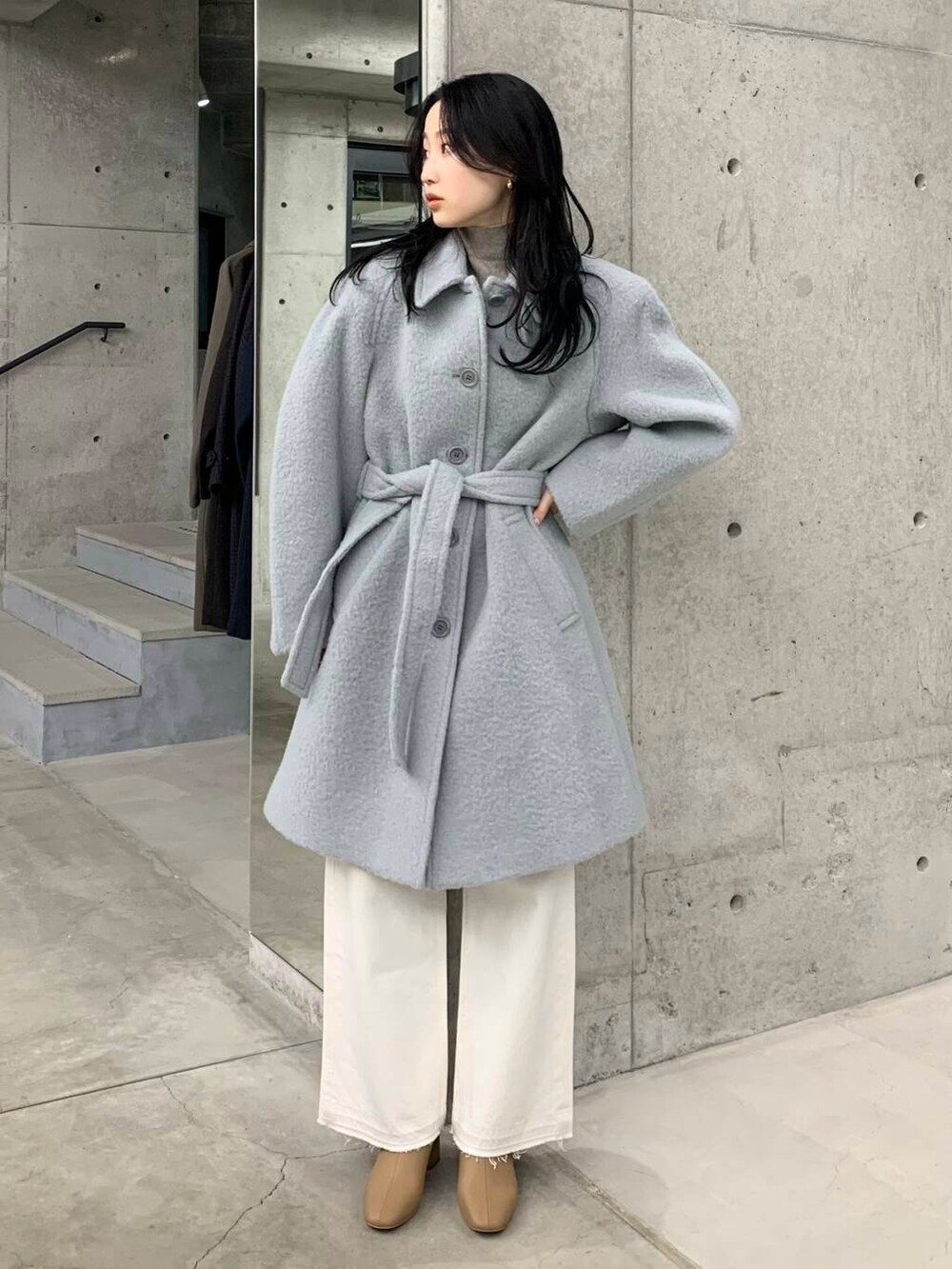 ホワイト系のデニムパンツ、ベージュ系のブーツ、ブルー系のステンカラーコートを着用したレディースの冬コーディネートの3枚目の写真