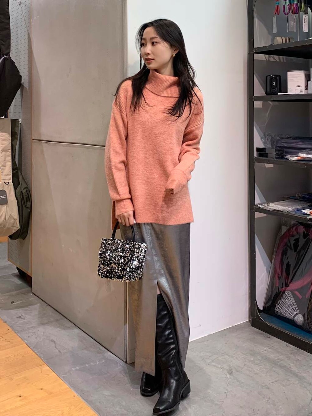 シルバー系のショルダーバッグ、ブラック系のブーツ、シルバー系のスカートを着用したレディースの冬コーディネートの3枚目の写真