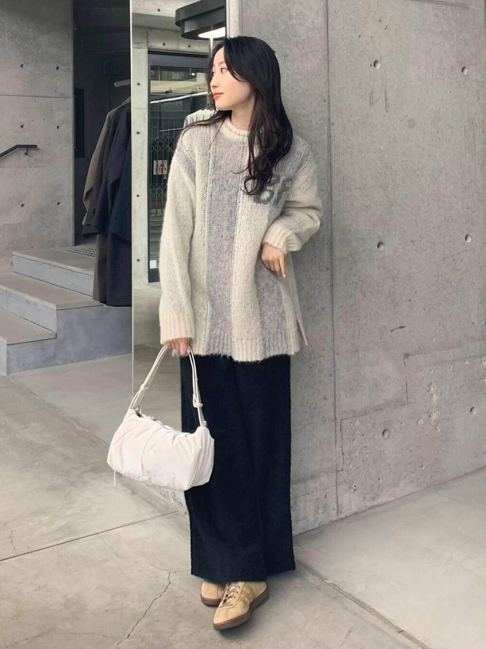 ブラック系のその他パンツ、グリーン系のニット/セーター、ホワイト系のショルダーバッグを着用したレディースの冬コーディネートの2枚目の写真