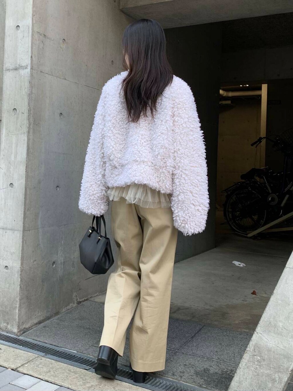 ブラック系のショルダーバッグ、ブラック系のブーツ、ベージュ系のチノパンツを着用したレディースの冬コーディネートの7枚目の写真