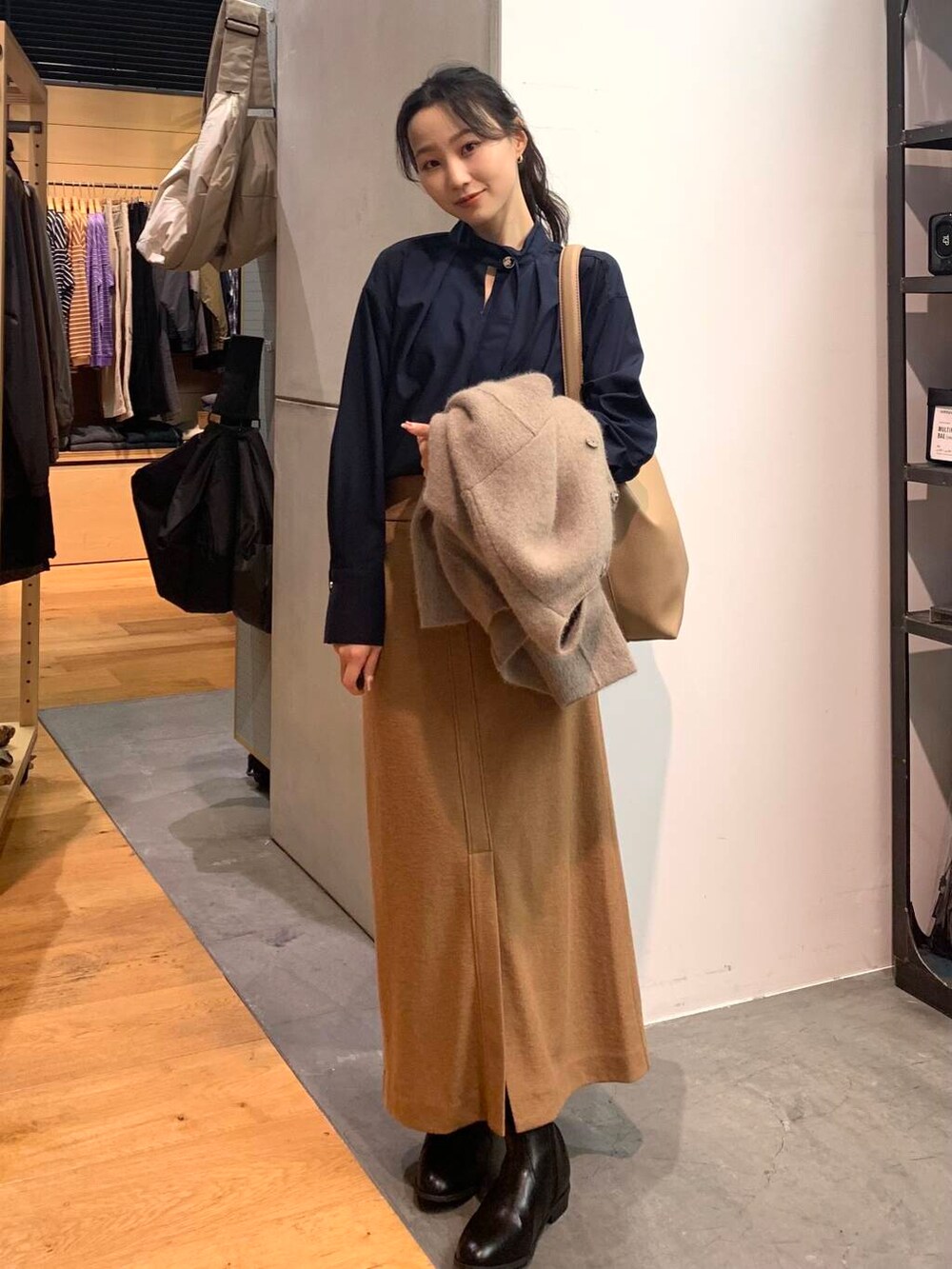 ブラック系のブーツ、ブラウン系のカーディガン/ボレロ、ベージュ系のトートバッグを着用したレディースの秋コーディネートの2枚目の写真