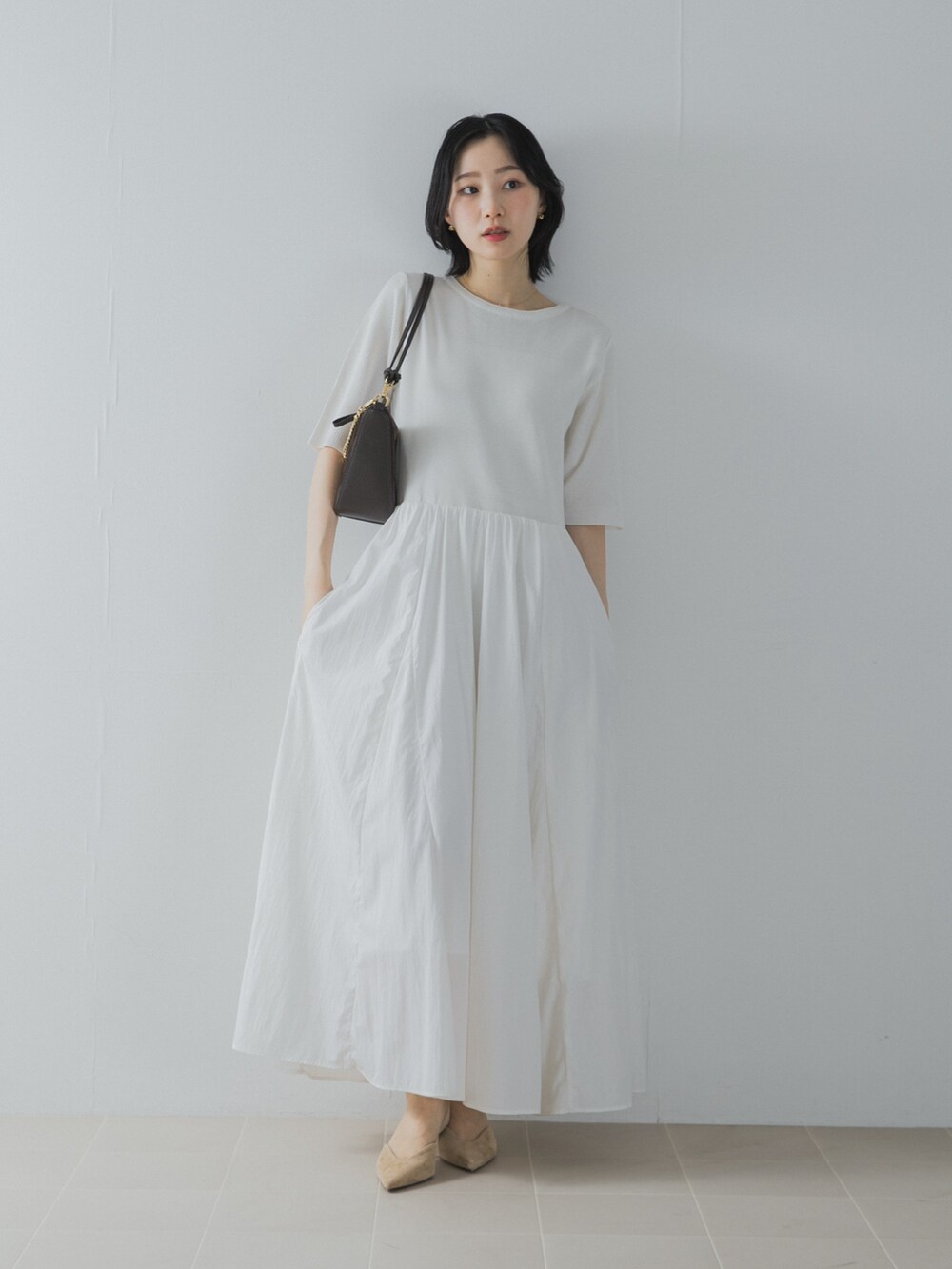 ホワイト系のワンピース、ブラウン系のショルダーバッグ、ベージュ系のパンプスを着用したレディースの夏コーディネートの3枚目の写真