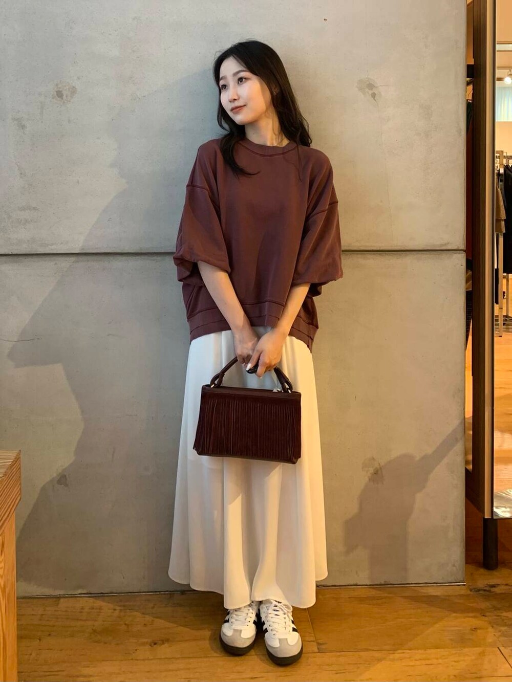 ホワイト系のスカート、ホワイト系のスニーカー、ブラウン系のTシャツ/カットソーを着用したレディースの夏コーディネートの2枚目の写真