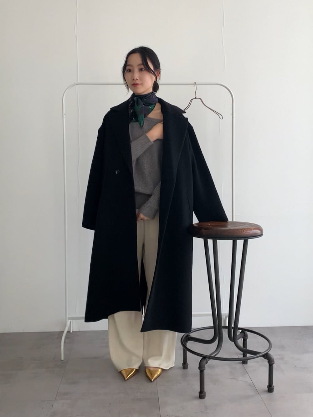 グレー系のニット/セーター、ホワイト系のその他パンツ、ブラック系のチェスターコートを着用したレディースの冬コーディネートの2枚目の写真